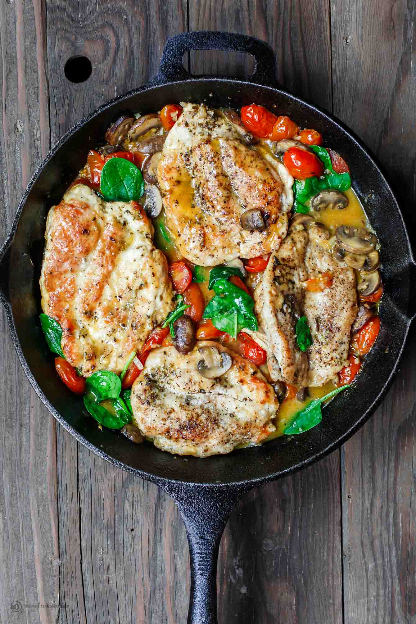 30-Minute Italian Skillet Chicken Recipe with Tomatoes and Mushrooms | The Mediterranean Dish. Flavor packed chicken breasts cooked in white wine with mushrooms, tomatoes and more! The perfect weeknight dinner in minutes! See the recipe on TheMediterraneanDish.com